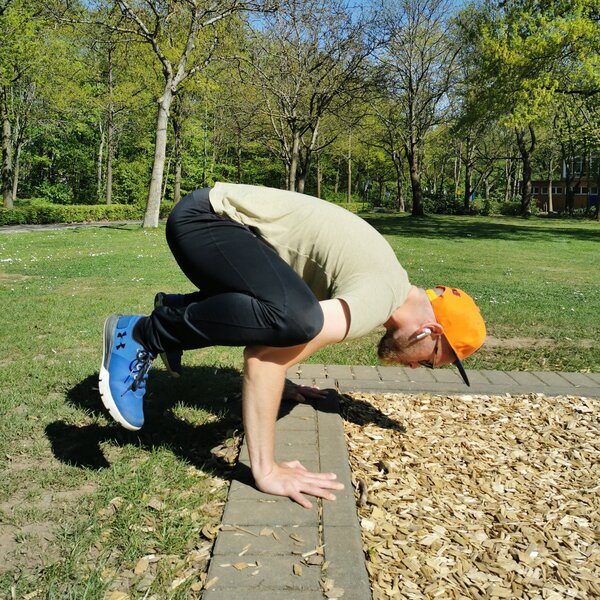 Panagiotis Giannikakis bei einer Crow-Pose im Park